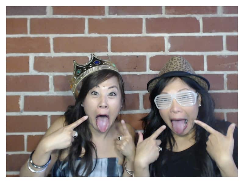 two girls sticking tongues out in front of brick wall