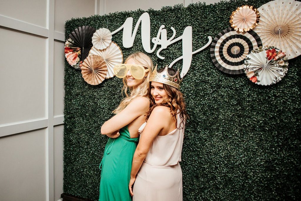 women posing for photo in front of beautiful vine wall