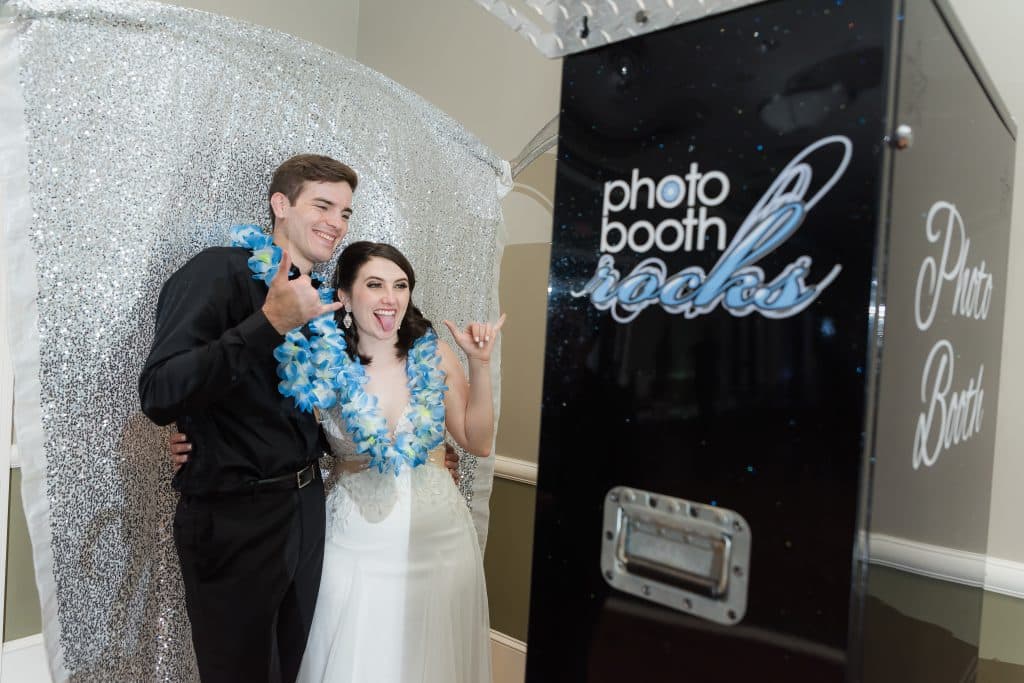 bride and groom wearing blue leis in photo booth