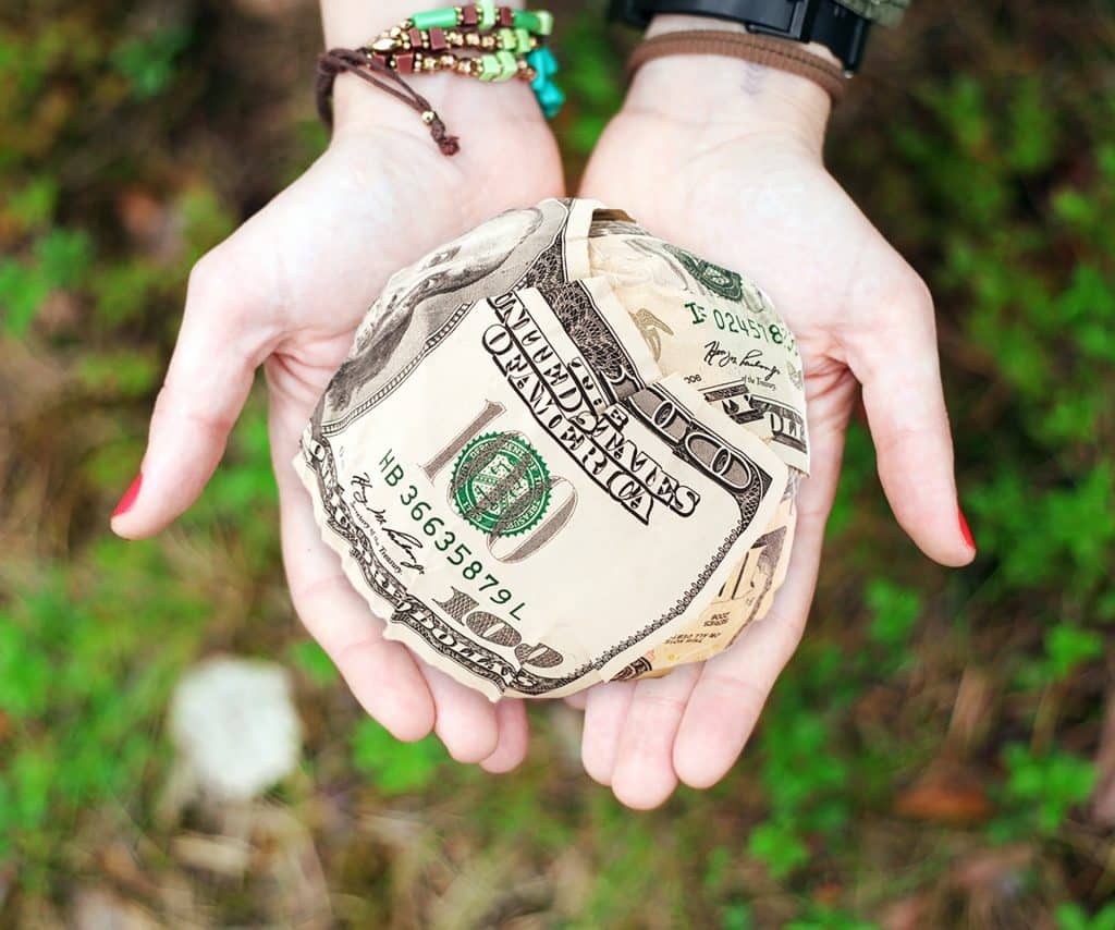 hands holding ball made of money