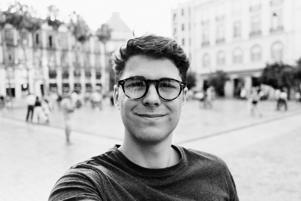 black and white selfie of man in city courtyard