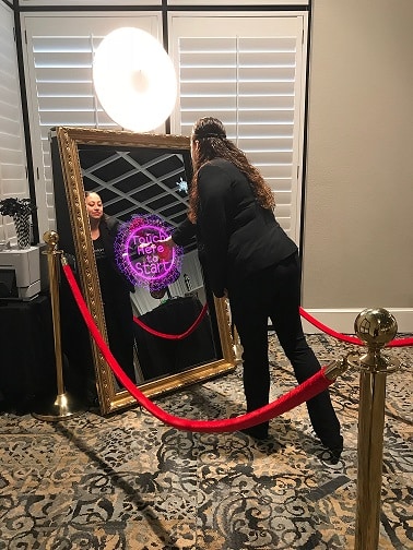 Woman using the touch screen on the mirror photo booth to take a fun picture at an event