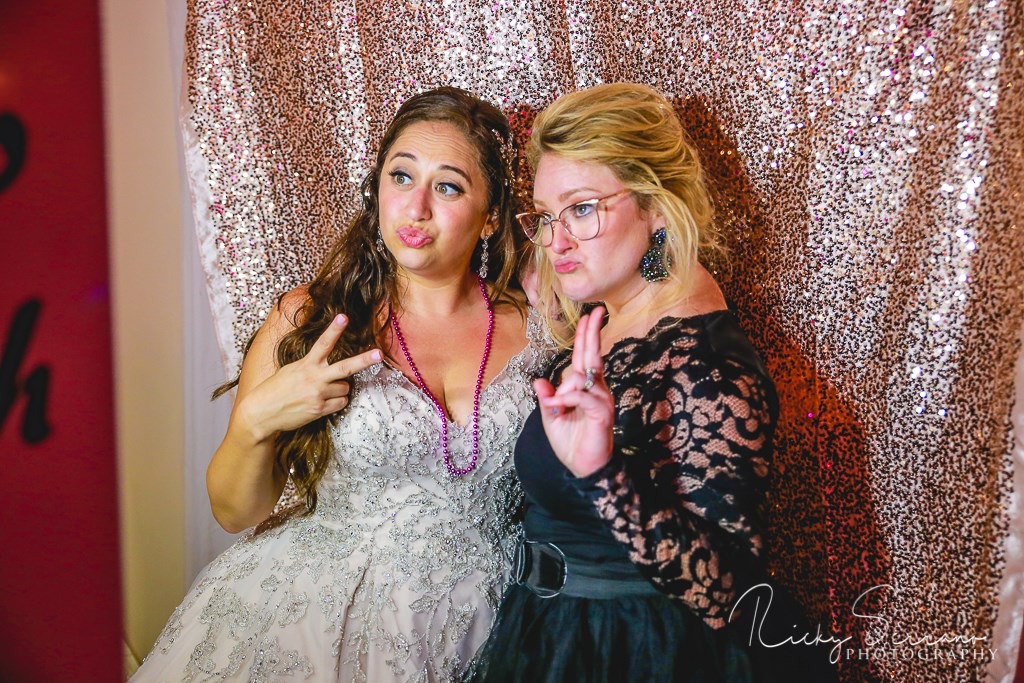 Two women holding up peace sign s their photo booth pose.