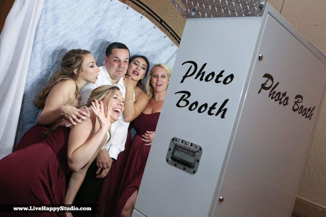 Bridesmaids and groom posing in photo booth.