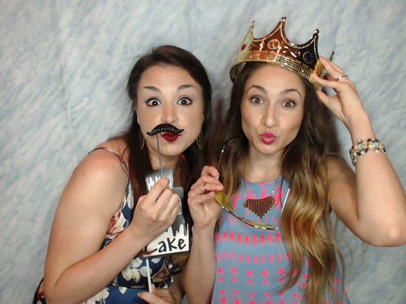 Two girls with prop mustaches in photo booth.