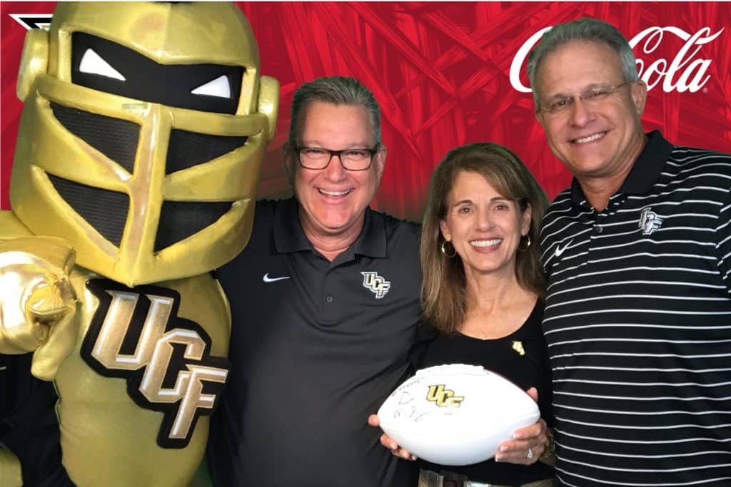 The UCF mascot and guests pose in front of a custom green screen backdrop.