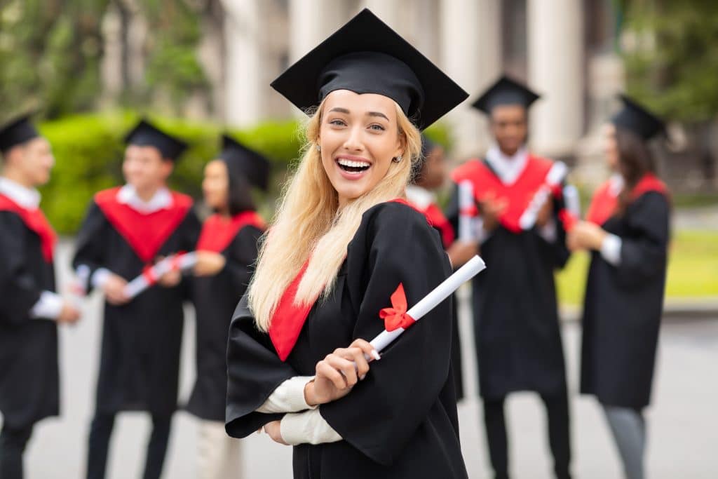 A young woman smiling in her graduation cap and gown.