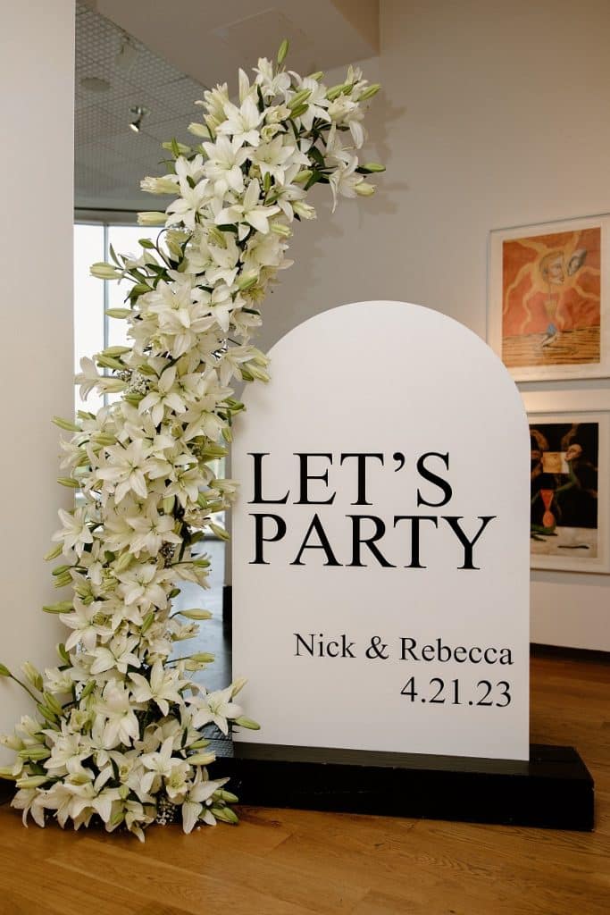 Sign with floral arch reading "Let's Party"